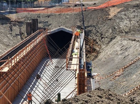 A construction site with workers standing on the ground.