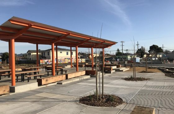 A park with benches and tables in the middle of it.