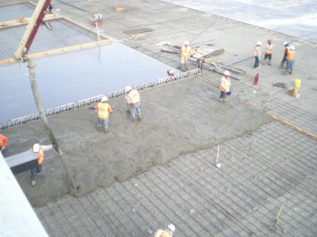 A group of construction workers standing on top of cement.