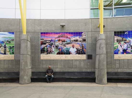 A man sitting on the ground in front of a large poster.