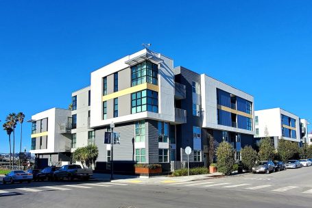 A building with many windows on the corner of a street.