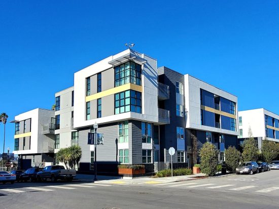 A building with many windows on the corner of a street.