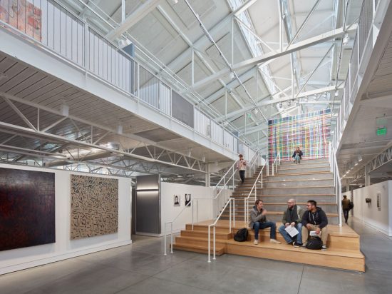 A group of people sitting on steps in an open building.