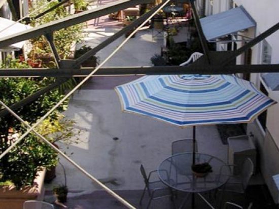 A patio with an umbrella and tables in the middle of it.